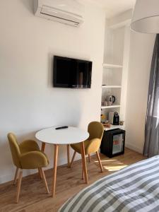 um quarto com uma mesa e duas cadeiras e uma televisão em B&B SU SICCU em Cagliari