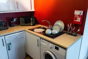 a kitchen with a sink and a washing machine at Cozy and Modern 2-bed apartment in Swansea