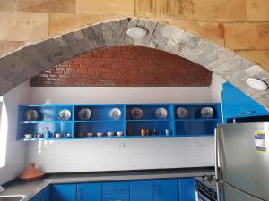 a kitchen with blue cabinets and a brick wall at Laila Flat in Al Aqālitah