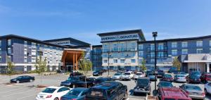 Un estacionamiento con autos estacionados frente a un edificio. en Sandman Signature Langley Hotel, en Langley