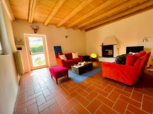 Elle comprend un salon doté d'un mobilier rouge et d'une cheminée. dans l'établissement Casa Indipendente - Vasto Parco Naturale & Lago di Lugano, à Cuasso Al Monte