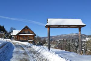 a wooden house in the snow next to a road at Sarni Szlak in Zawoja