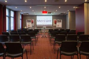 a conference room with a projector screen and chairs at Mercure Trouville Sur Mer in Trouville-sur-Mer