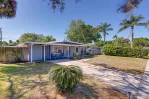 a small white house with a palm tree at Titusville Vacation Rental with Private Pool! in Titusville