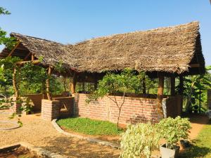 uma casa com telhado de palha e um quintal em Hotel Hanguk Villa em Dambulla