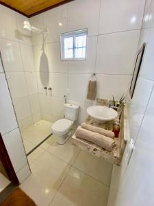 La salle de bains blanche est pourvue de toilettes et d'un lavabo. dans l'établissement Quartos Dossel - Sítio Belo Monte, à Pacoti