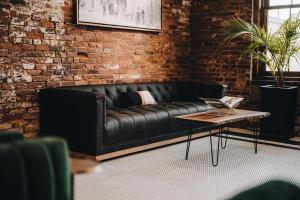 um sofá de couro preto num quarto de tijolos com uma mesa de centro em The Chandler Hotel em Madison