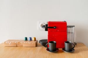 a red appliance sitting on top of a table with cups at Le Charmant Hypercentre tram design in Saint-Étienne