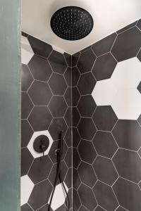 a shower with black and white tiles in a bathroom at Le Charmant Hypercentre tram design in Saint-Étienne