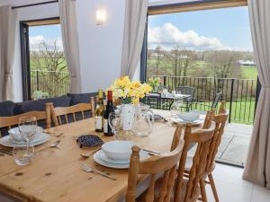 a dining room table with a view of a balcony at Woodpecker Lodge in Cullompton