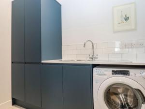 a kitchen with a washing machine and a sink at Woodpecker Lodge in Cullompton