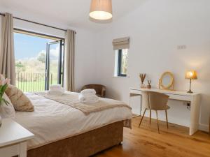 1 dormitorio con cama, escritorio y ventana en Woodpecker Lodge en Cullompton
