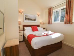 a bedroom with a bed with red and white sheets at Chalet Log Cabin C11 in Ilfracombe