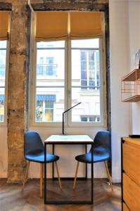 een tafel en twee stoelen voor een raam bij Le Bleu hypercentre Presque île in Lyon