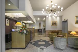 a lobby with a reception desk and chairs and aandelier at Hotel Falco D'Oro in Tolè