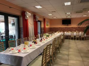 Szalowa Sport Arena في Szalowa: طاولة طويلة في غرفة مع طاولات وكراسي