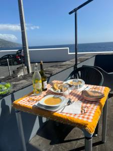 einen Tisch mit einem Teller Essen und zwei Flaschen Wein in der Unterkunft Casa da Bicuda in Ribeiras