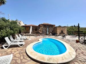 a swimming pool with chairs and a house at Caserio rural antiguo con espectacular piscina y Wifi en San Miguel de Abona, Tenerife Sur in San Miguel de Abona