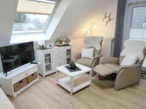 a living room with a flat screen tv and chairs at Mellum in Norden