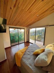 a bedroom with a large bed with large windows at Hermosa casa privada con jacuzzi y una vista espectacular al lago in Valle de Bravo