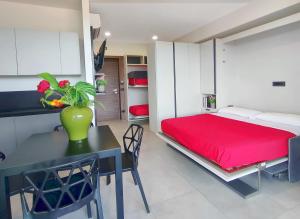 1 dormitorio con cama roja, mesa y sillas en Residence Hotel Margherita, en Montalto di Castro
