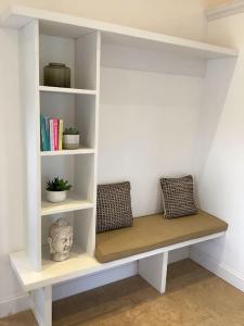 a white book shelf with two pillows and a bust at Harcombe Barn near Bristol in Bristol