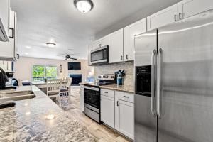 a kitchen with white cabinets and a stainless steel refrigerator at Bay Street Bliss in Gulf Breeze