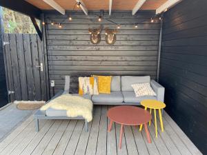 a patio with a couch and two tables and lights at Sfeervol guesthouse, privé tuin en free parking in Rotterdam