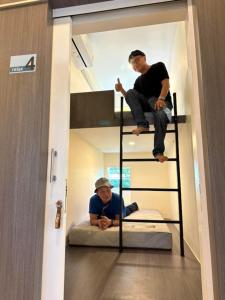 two men sitting on top of a bunk bed in a room at Norm Space Hostel NST in Nakhon Si Thammarat