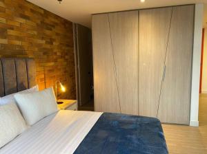 1 dormitorio con 1 cama grande y pared de ladrillo en Apartamento 512 academia, en Bogotá