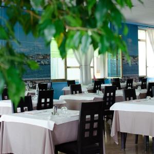 ブレシアにあるHotel Industriaの白いテーブルと椅子、大きな窓のあるレストラン