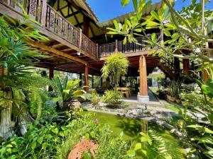 a large wooden house with a balcony in a garden at La Maison - Chiangmai in Mae Taeng