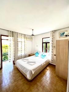 1 dormitorio con 1 cama blanca grande con almohadas azules en Salina Pansiyon, en Kas