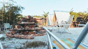 a pile of logs sitting next to some chairs at Casa São Lourenço in Bertioga