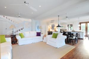 a living room with two white couches and a kitchen at Alfred House home in Governorʼs Harbour