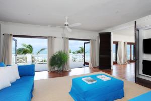 ein Wohnzimmer mit einem blauen Sofa und einem TV in der Unterkunft Alfred House home in Governors Harbour