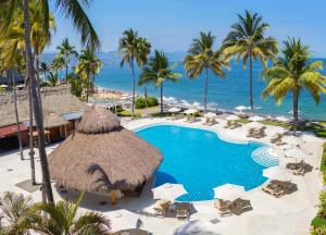 a resort with a swimming pool and palm trees and the ocean at Plaza Pelicanos Club Beach Resort All Inclusive in Puerto Vallarta