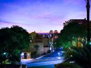 uma rua da cidade à noite com palmeiras e edifícios em Marbella Elviria apartment em Marbella