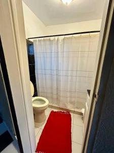 baño con aseo y alfombra roja en Casa Carlota en Tijuana