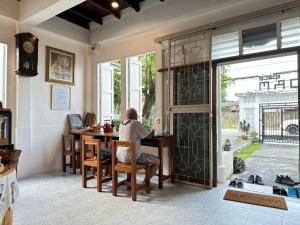 a person sitting at a table in a house at Norm Space Hostel NST in Nakhon Si Thammarat