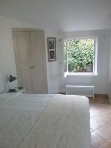 a white bedroom with a bed and a window at UNE CHAMBRE EN VILLE in L'Isle-sur-la-Sorgue
