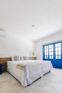 a white bedroom with a large bed with blue doors at Pousada Villa Santô in Guarujá
