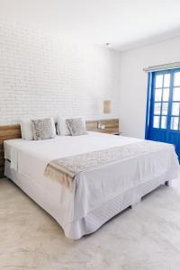 a bedroom with a large white bed with a blue door at Pousada Villa Santô in Guarujá