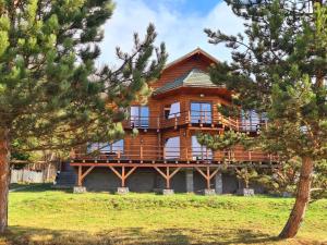 a large wooden house with a balcony on top of it at Lucky Rönk vendégház in Vîlcele