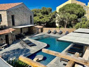 a swimming pool with chairs and a building at Hôtel Casa Rossa & Spa in LʼÎle-Rousse
