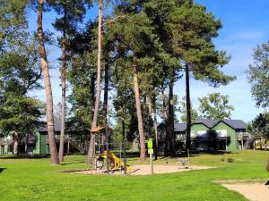 a playground in a park with trees and a yellow swing at Appartement Shakespeare 15 in Chaveignes