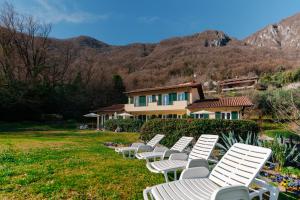 a row of white lawn chairs in front of a house at Villa Oliveto apartments in Oliveto Lario
