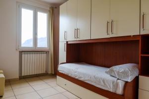 1 dormitorio con 1 cama con armarios blancos y ventana en Villa Oliveto apartments, en Oliveto Lario