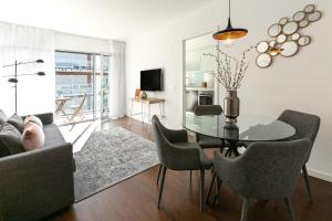uma sala de estar com uma mesa de vidro e cadeiras em Lisbon Metro & Pool Apartment em Lisboa