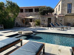 a swimming pool with lounge chairs and a building at Hôtel Casa Rossa & Spa in LʼÎle-Rousse